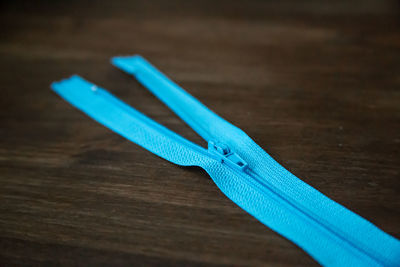 Close-up of blue zipper on wooden table