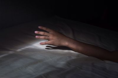 Close-up of person hand on bed