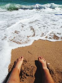 Low section of woman sitting at beach