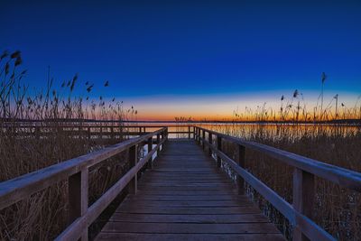 Boardwalk on footbridge against clear blue sky