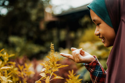 Side view of cute smiling girl looking at plant