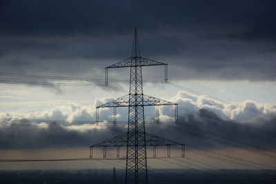 Low angle view of electricity pylon against dramatic sky during sunrise 