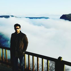 Portrait of young man standing on mountain against foggy weather