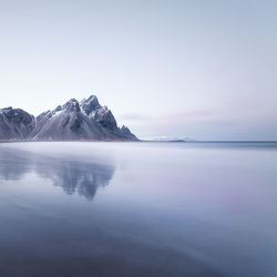 Scenic view of lake by snowcapped mountains against sky