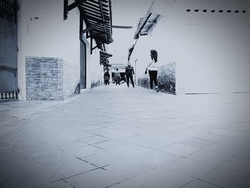 People walking on footpath amidst buildings in city