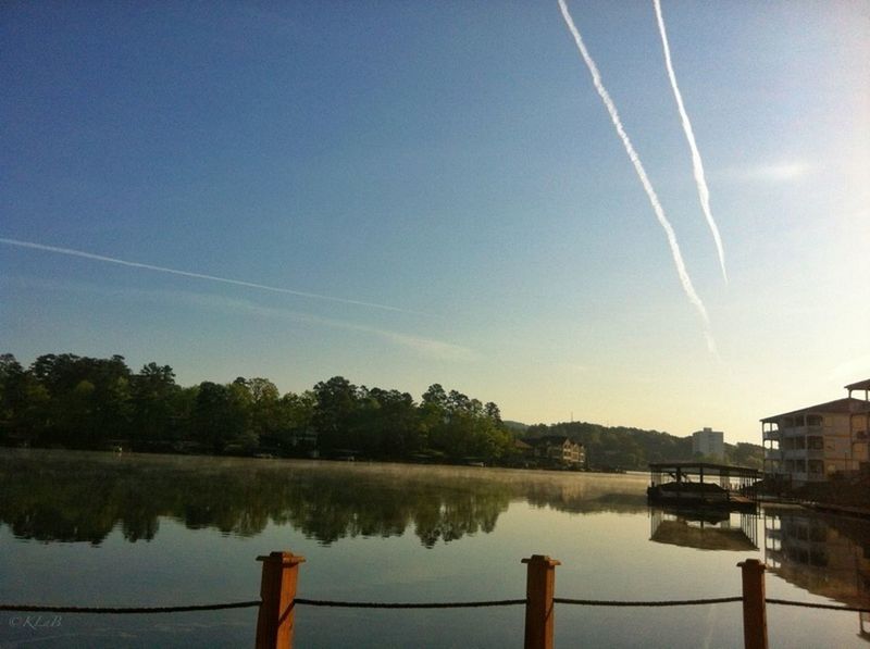 water, lake, reflection, tranquil scene, tranquility, sky, scenics, beauty in nature, waterfront, nature, blue, river, tree, outdoors, calm, idyllic, no people, built structure, day, vapor trail