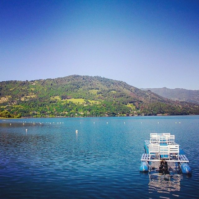 water, mountain, clear sky, blue, nautical vessel, tranquil scene, lake, tranquility, copy space, boat, scenics, transportation, mountain range, beauty in nature, mode of transport, nature, moored, waterfront, idyllic, day