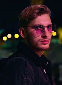 Portrait of young man wearing eyeglasses while standing at night