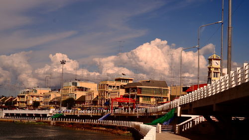 Bridge over river by buildings in city against sky