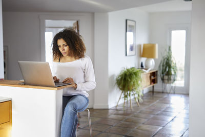 Woman using laptop computer on table at home