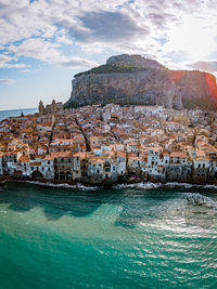 View of town by sea against cloudy sky