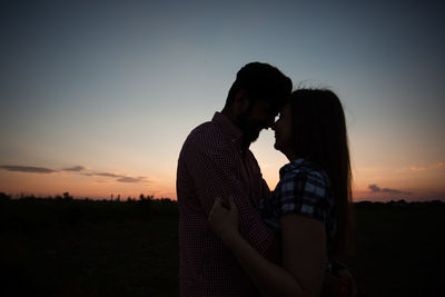 Couple kissing against sky during sunset