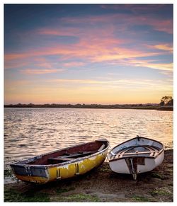 Boats moored on lake against sky during sunset