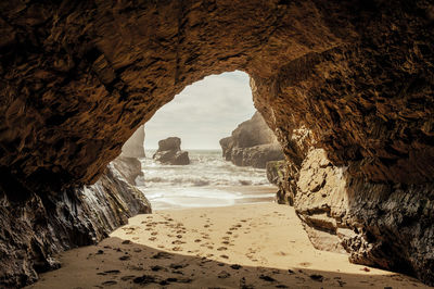 Scenic view of beach seen through cave