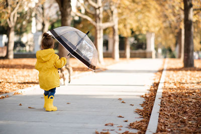 Full length of woman with umbrella walking on road