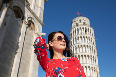 Woman with hand in hair standing against leaning tower of pisa in italy