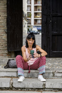 Woman using mobile phone sitting on steps