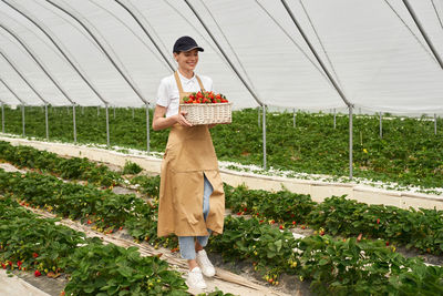 Portrait of smiling young woman standing in greenhouse