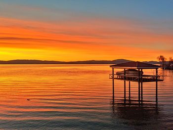 Red sky and golden light reflecting on the water against mountain silhouette.