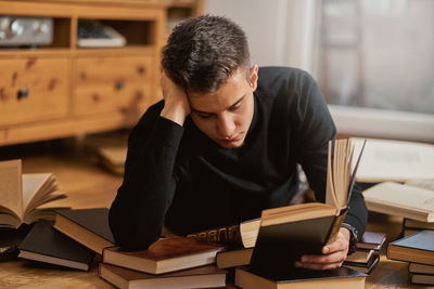 Man reading book while lying on floor at home