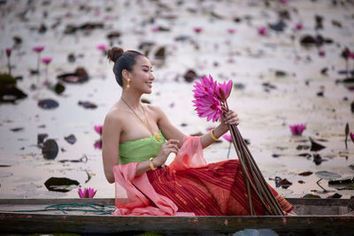 Woman holding lotus while sitting on boat in lake