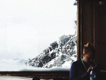 Woman standing on snow covered mountain against sky