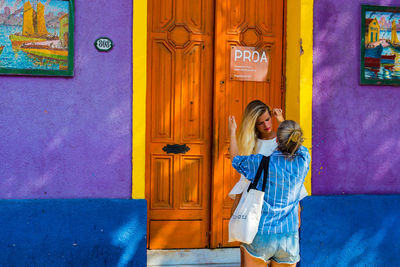 Woman standing against blue door