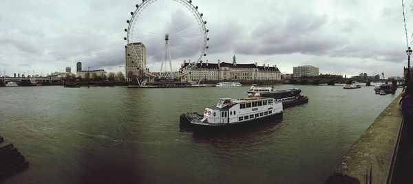 Boats at harbor against cloudy sky