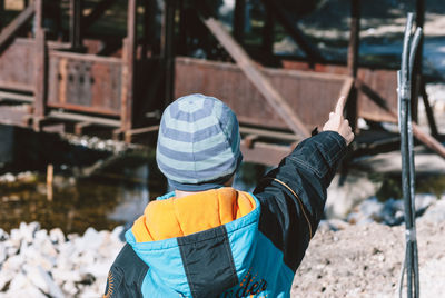 Rear view of boy gesturing during sunny day