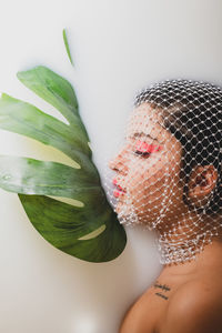 Young woman with face covered by net taking milk bath