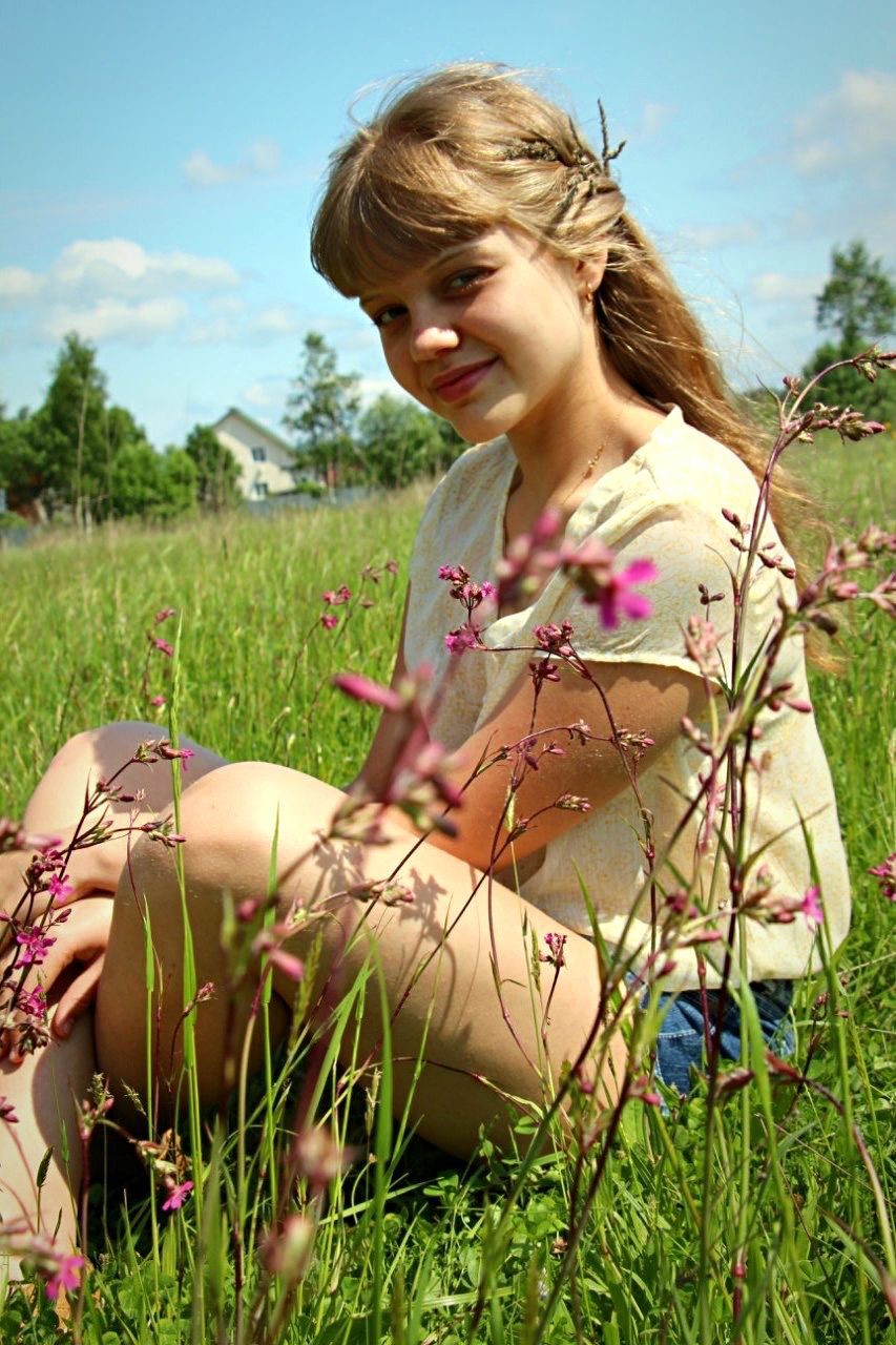 person, grass, young adult, lifestyles, leisure activity, casual clothing, field, looking at camera, young women, grassy, plant, front view, smiling, portrait, happiness, focus on foreground, nature, three quarter length