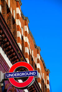 Low angle view of road sign against blue sky