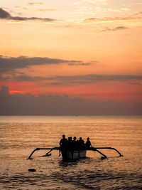 Silhouette people in boat on sea against sky during sunset