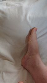 Close-up of human hand on bed