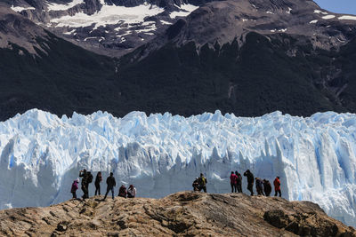 People hiking on snowcapped mountain during sunny day