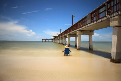 Rear view of man on pier over sea against sky