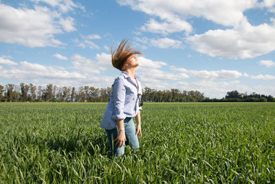 Rear view of woman standing on field against sky