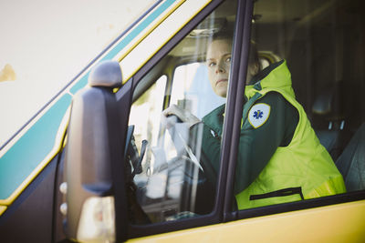 Female thoughtful rescue worker looking away while sitting in ambulance