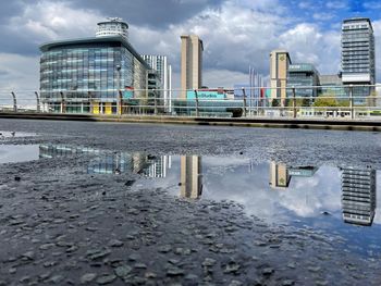 Reflection of building in puddle on city