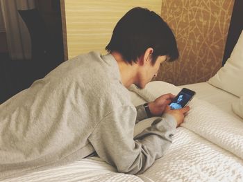 Man using mobile phone on bed at home