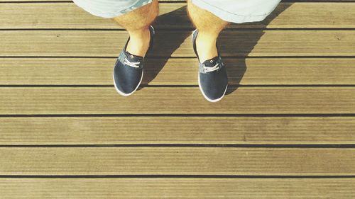 Low section of man wearing shoes standing on floorboard