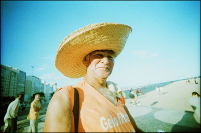 Portrait of man wearing hat against sky in city