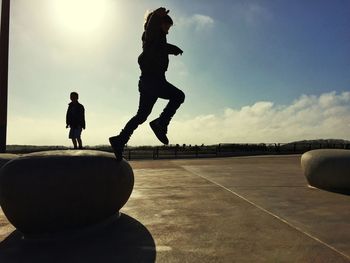 Silhouette friends jumping against sky at park during sunset