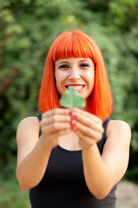 Portrait of smiling woman holding leaf outdoors