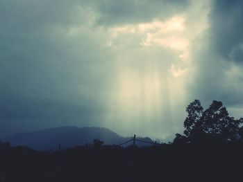 Low angle view of storm clouds over silhouette landscape