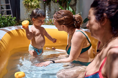 A girl, a grandmother and a little girl are playing in an inflatable pool. vacation concept