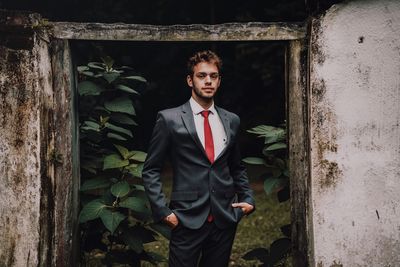 Portrait of young man standing against wall