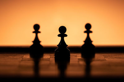 Close-up of silhouette lamp against orange sky