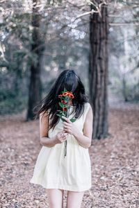 Midsection of woman standing by tree trunk in forest