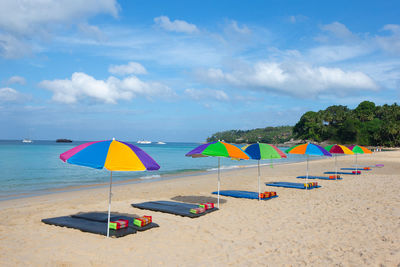 Multi colored umbrellas on beach against sky